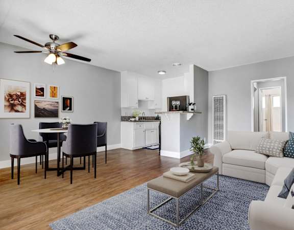 A living room with a white couch and a dining table with chairs.