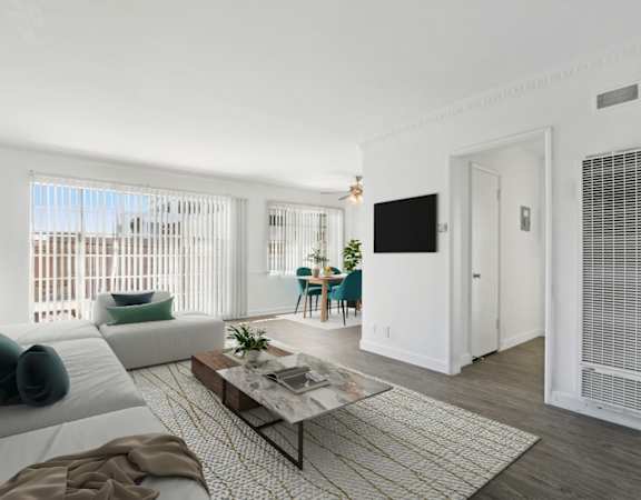 A living room with a white couch, a coffee table, and a television.