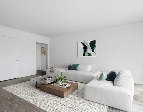 A white couch with green pillows sits in a room with a coffee table in front of it.