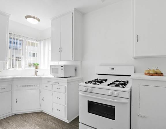 A white kitchen with a stove, oven, and microwave.