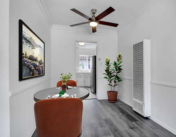 A room with a ceiling fan and a painting on the wall.