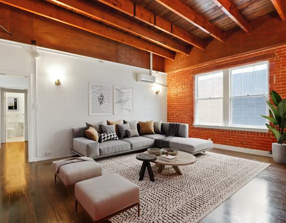 a living room with exposed brick walls and a gray couch