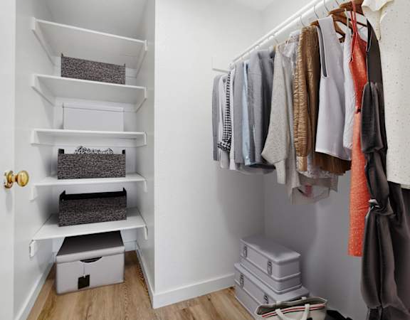 a small walk in closet with shelves and a rack of clothes