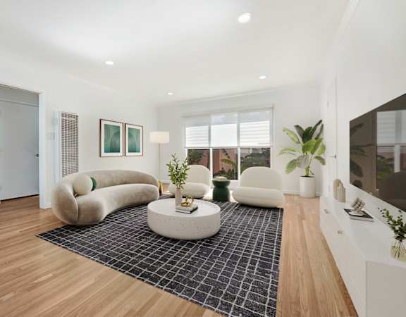 A living room with a white couch and a black and white rug.