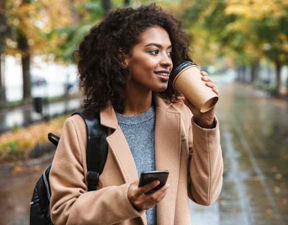 a woman holding a cell phone and a coffee cup