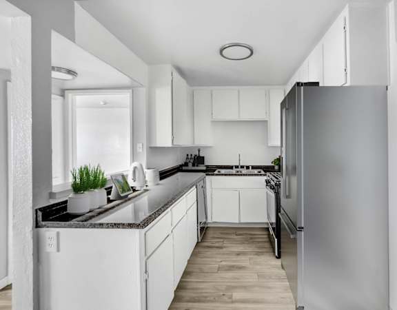 an empty kitchen with white cabinets and a stainless steel refrigerator