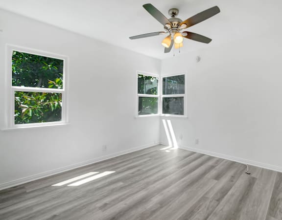 an empty room with white walls and a ceiling fan