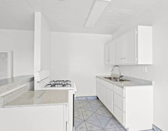 an empty kitchen with white cabinets and a counter top