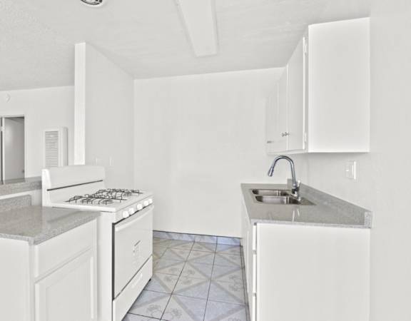 a kitchen with white cabinets and a sink and a stove