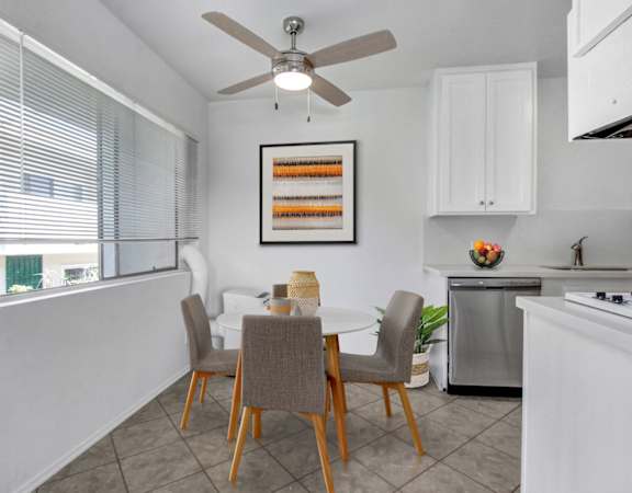 a dining area with a table and chairs and a ceiling fan