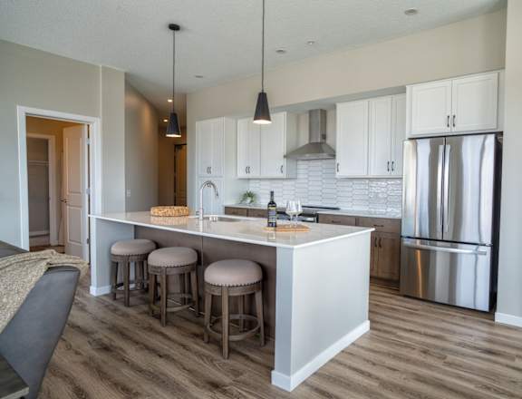 A kitchen with a white counter and stools.