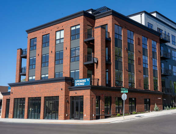 A red brick building with a blue sign that says "Opening Spring".