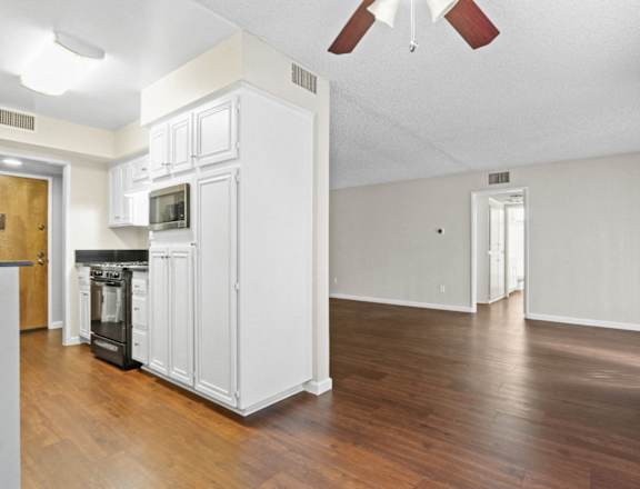 an empty living room with white cabinets and a wood floor