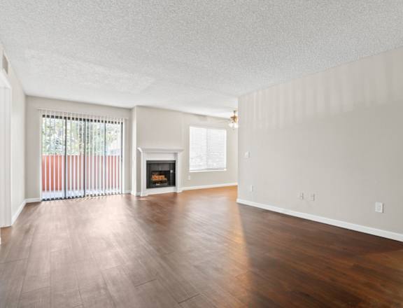 the spacious living room with wood flooring and a fireplace