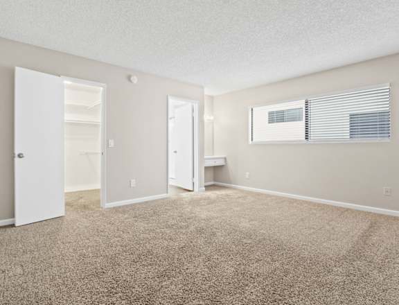 the spacious living room of an apartment with carpet and an open door to the bathroom