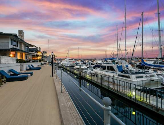 a marina at sunset with boats in the water and a house on the side of the