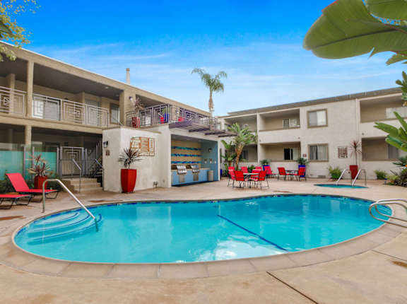 A swimming pool in a courtyard surrounded by chairs and buildings at Meridian Apartments, Los Angeles