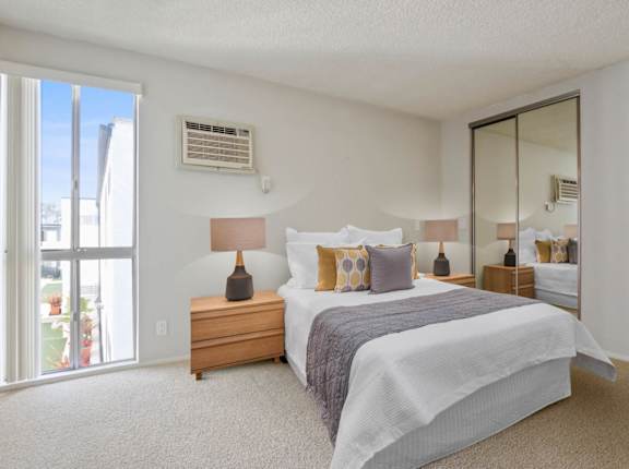 A bedroom with a bed, nightstand, and sliding glass doors at Rose Apartments, Los Angeles