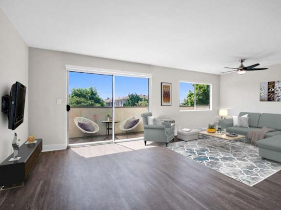 A living room with a grey couch, a television, and a fan.