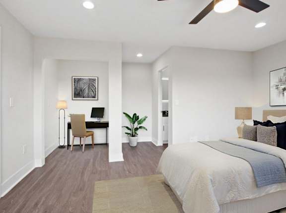 A bedroom with a large bed and a desk with a chair.