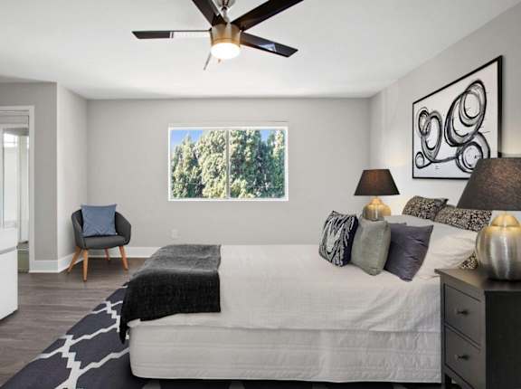 A bedroom with a bed, a chair, and a ceiling fan.