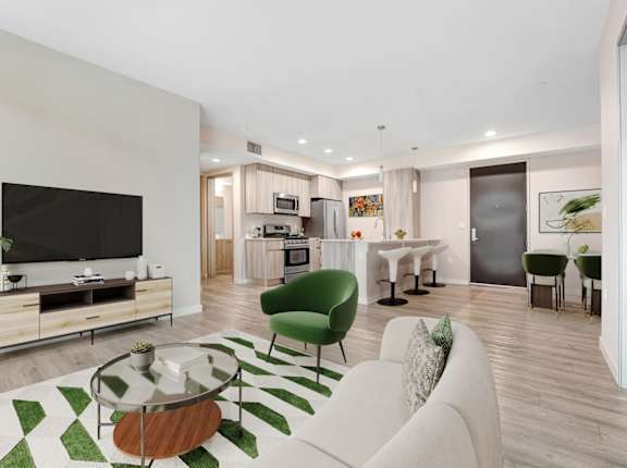 A modern living room with a green armchair and a glass coffee table.at The Blvd Lofts, Encino, 91436