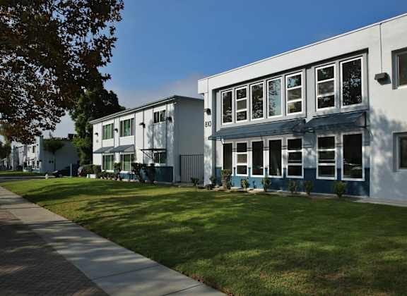 A white building with a blue trim is surrounded by a green lawn.