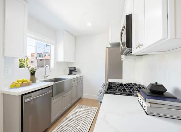 a white kitchen with stainless steel appliances and a window