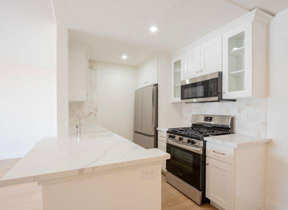 a kitchen with white cabinets and a stove and a refrigerator
