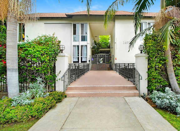 a house with palm trees and a sidewalk in front of it