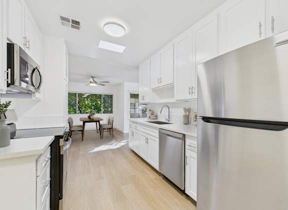 A modern kitchen with white cabinets and stainless steel appliances.