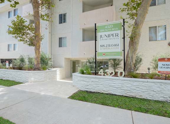 a building with a sign in front of it with grass and trees