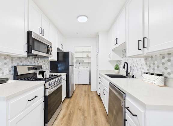 A kitchen with white cabinets and black appliances.