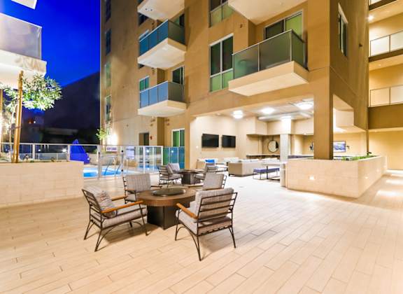 A patio with a table and chairs is surrounded by apartment buildings.