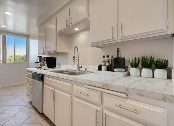 an open kitchen with white cabinets and marble counter tops and a sink