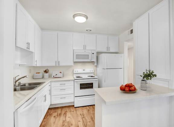 A kitchen with white cabinets and appliances.