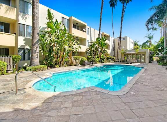 a large swimming pool in front of a hotel with palm trees