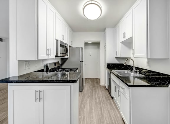 a white kitchen with white cabinets and black counter tops