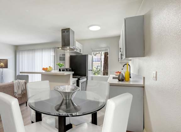 a kitchen and dining room with white chairs and a glass table