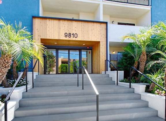 the entrance to a building with stairs and palm trees