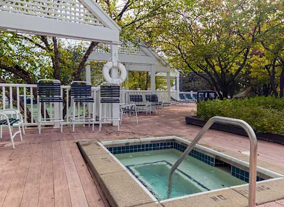 a hot tub in the middle of a deck with chairs at Village Club of Farmington Hills, Farmington Hills, 48331