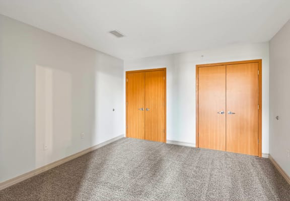 A room with two wooden doors and carpeted floor.
