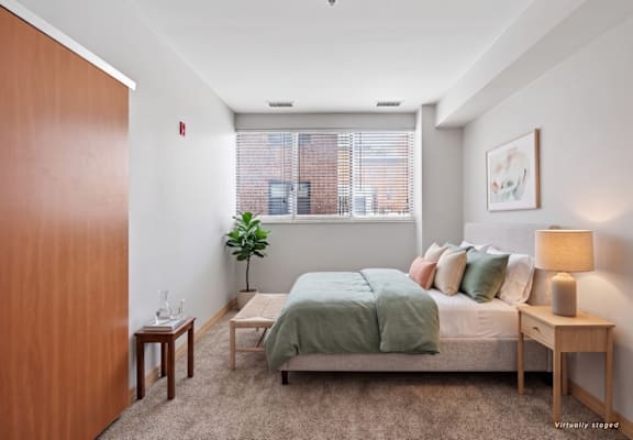 A bedroom with a bed, nightstand, and window.