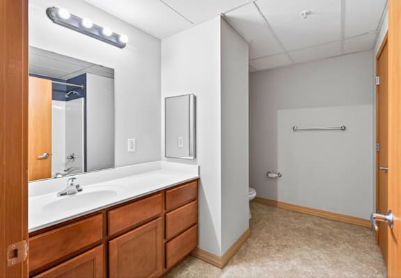 A bathroom with a sink, mirror, and towel bar.