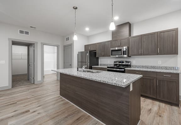 A modern kitchen with a granite countertop and wooden cabinets.