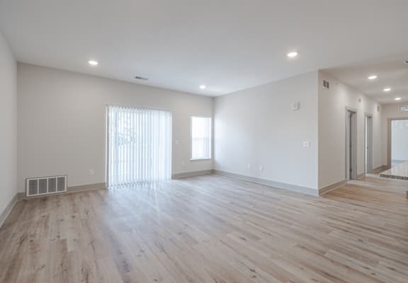 A spacious room with wooden flooring and white walls.