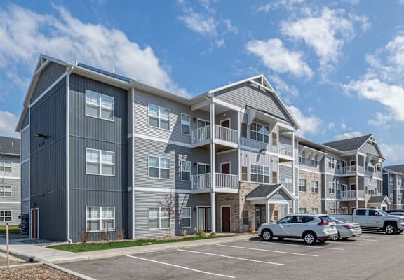 A row of modern apartment buildings with cars parked in front.