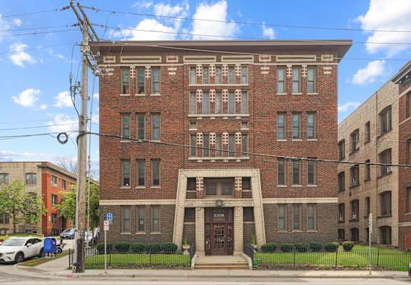 A red brick building with a black fence in front.