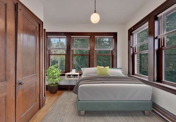 A bedroom with a bed, nightstand, and window.