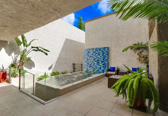 A modern outdoor patio with a fountain and chairs at Meridian Apartments, Los Angeles, California
